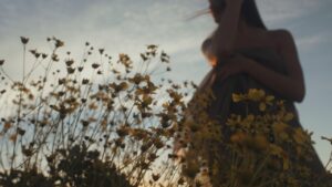 bottom view of a woman dancing in a field of flowers with the sky as her background